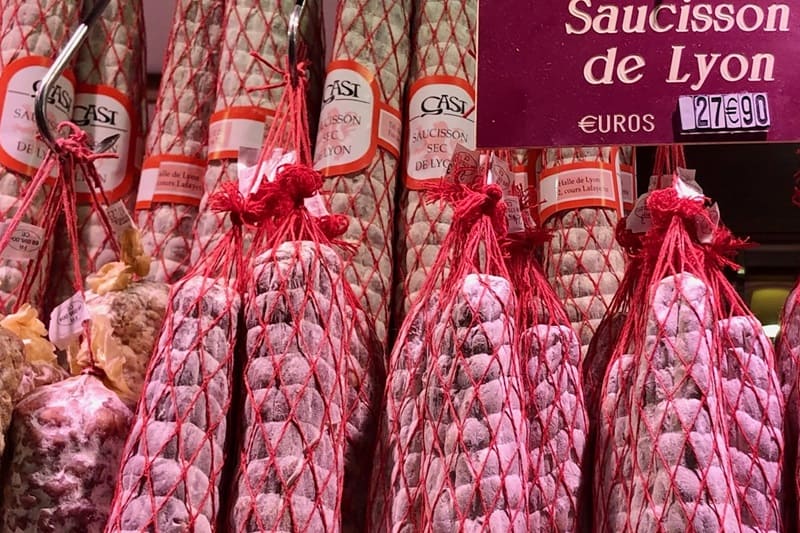 Sausages of Lyon in red bags hanging in a market.