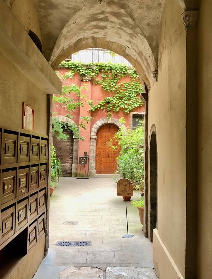 Lyon traboule, or secret passageway, opening out into a courtyard with arched doors and lots of plants.